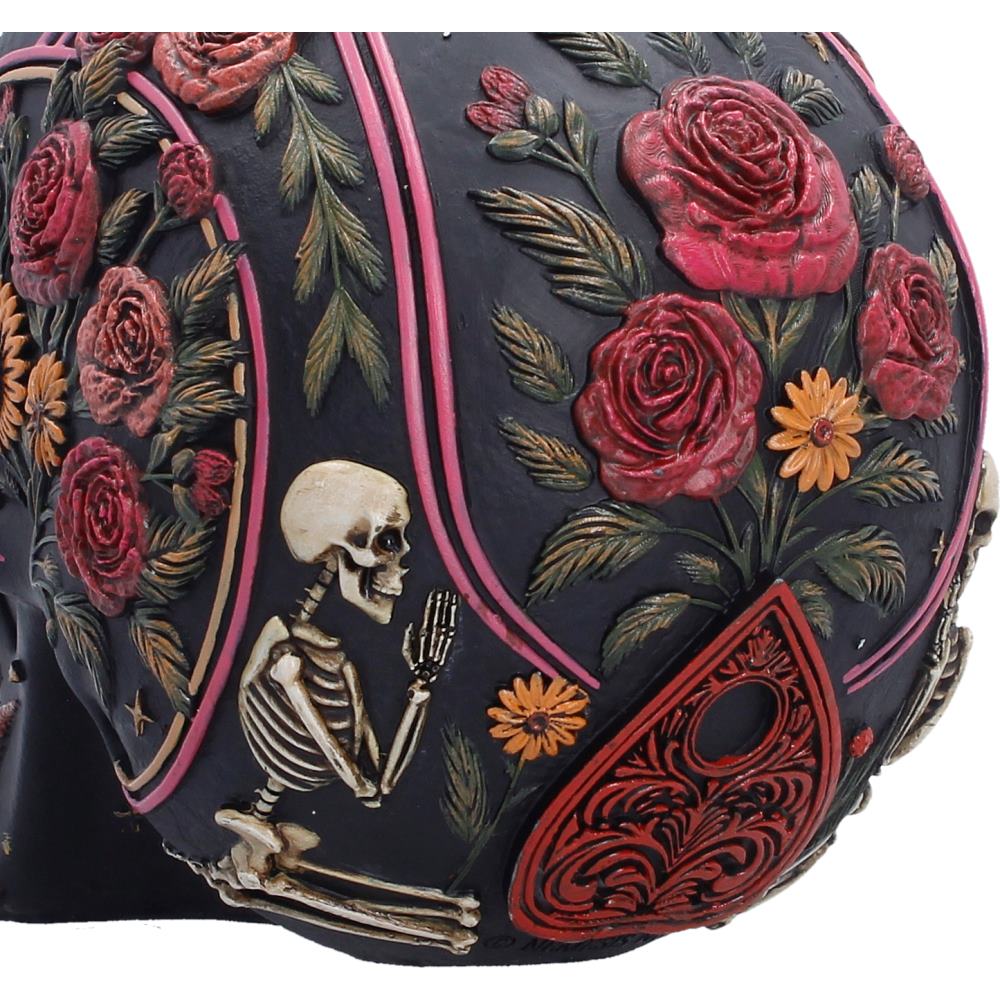 Close-up of the colourful floral detailing on the Spirit Board Bloom Skull featuring a dark navy base with raised red and pink roses, green leaves, small orange flowers, a kneeling skeleton figure, and a red teardrop-shaped motif.
