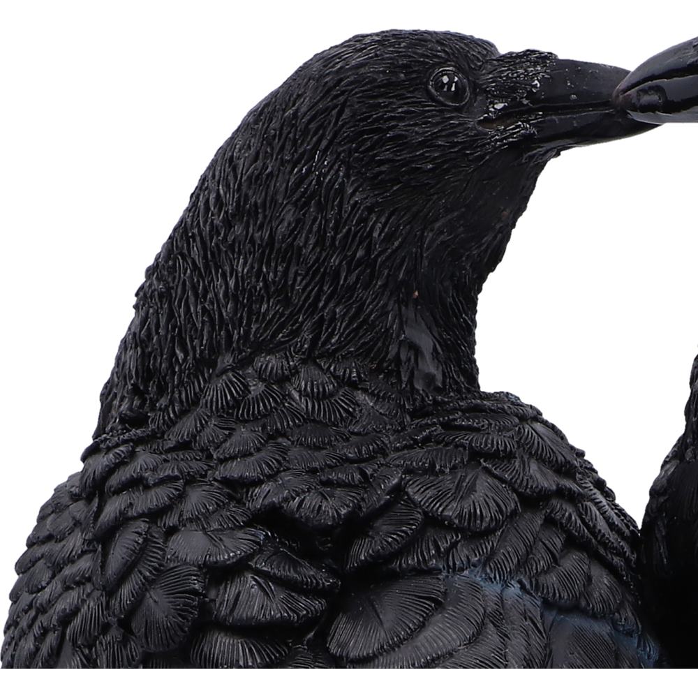Close-up of a black raven figurine showing detailed textured feathers, a dark beak, and a glossy eye